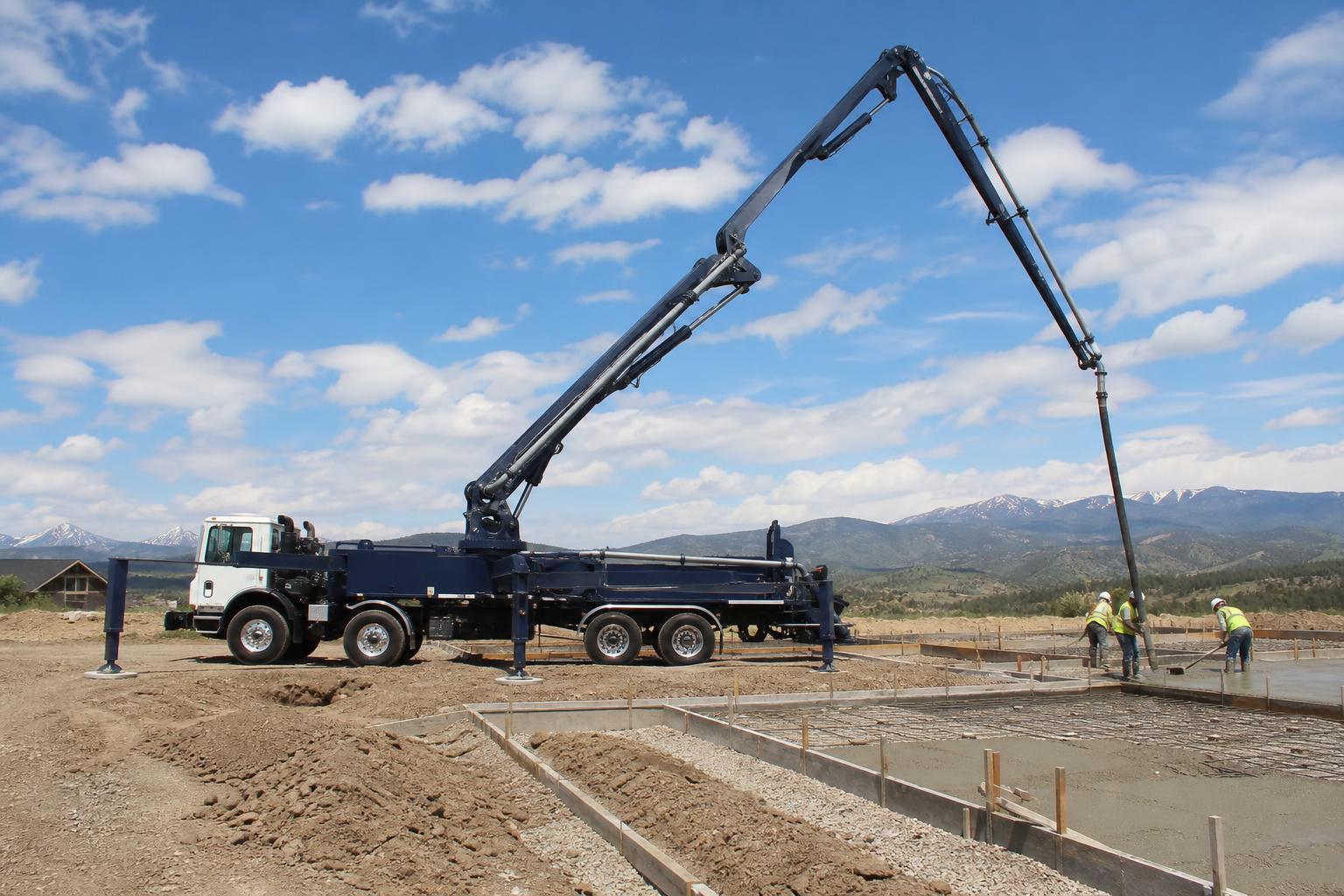 Fully extended concrete boom pump truck delivering concrete on a Denver commercial construction project.